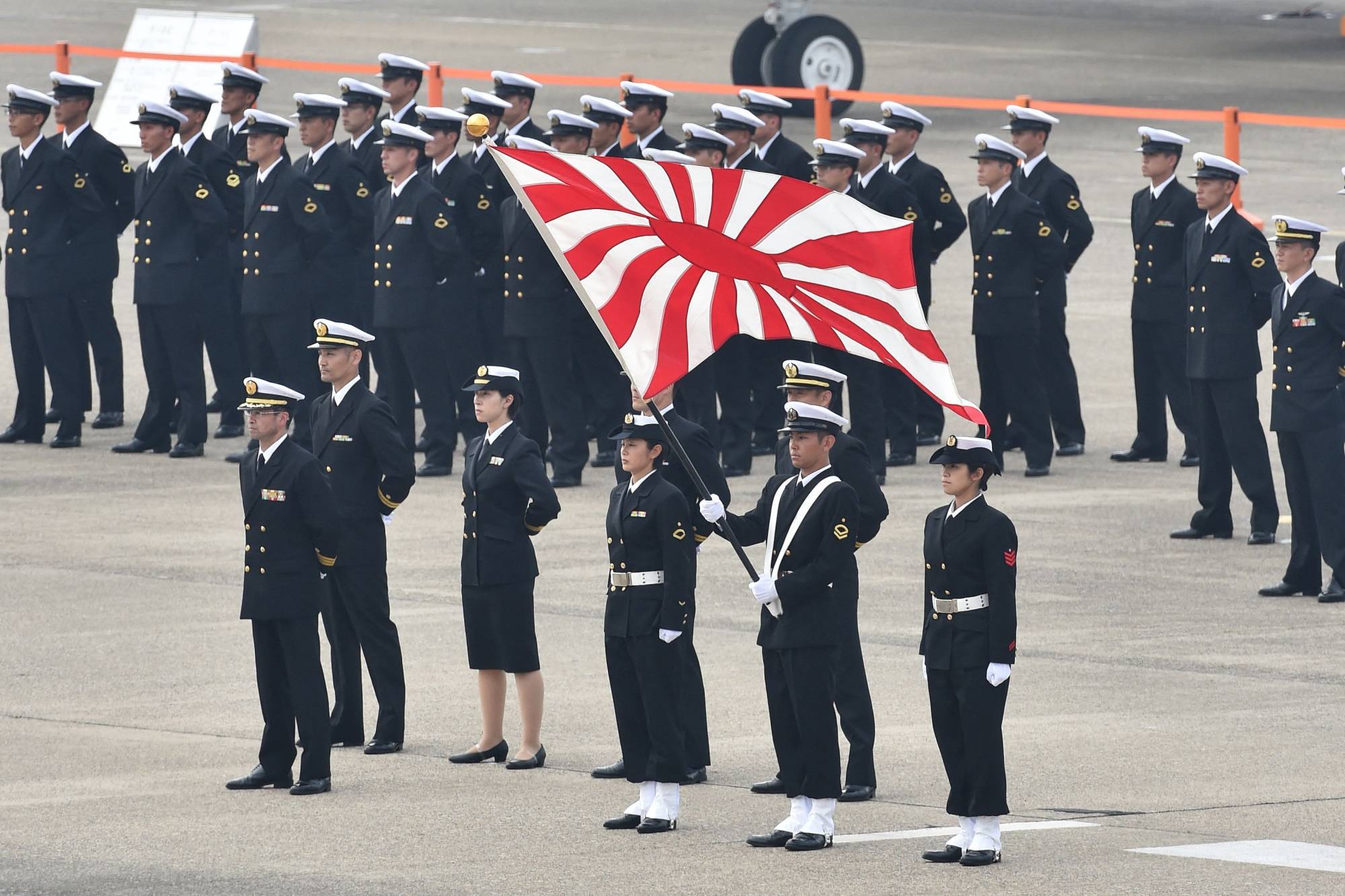 Self-Defense Force service members stand with the naval flag prior to a review ceremony on a runway at the Air Self-Defense Force's Hyakuri Air Base in Omitama, Ibaraki Prefecture, in October 2014. | AFP-JIJI