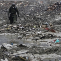 A Self-Defense Force member searches for victims in an area devastated in the March 11, 2011, earthquake and tsunami, in Minamisanriku, Miyagi Prefecture, in April 2011. | REUTERS