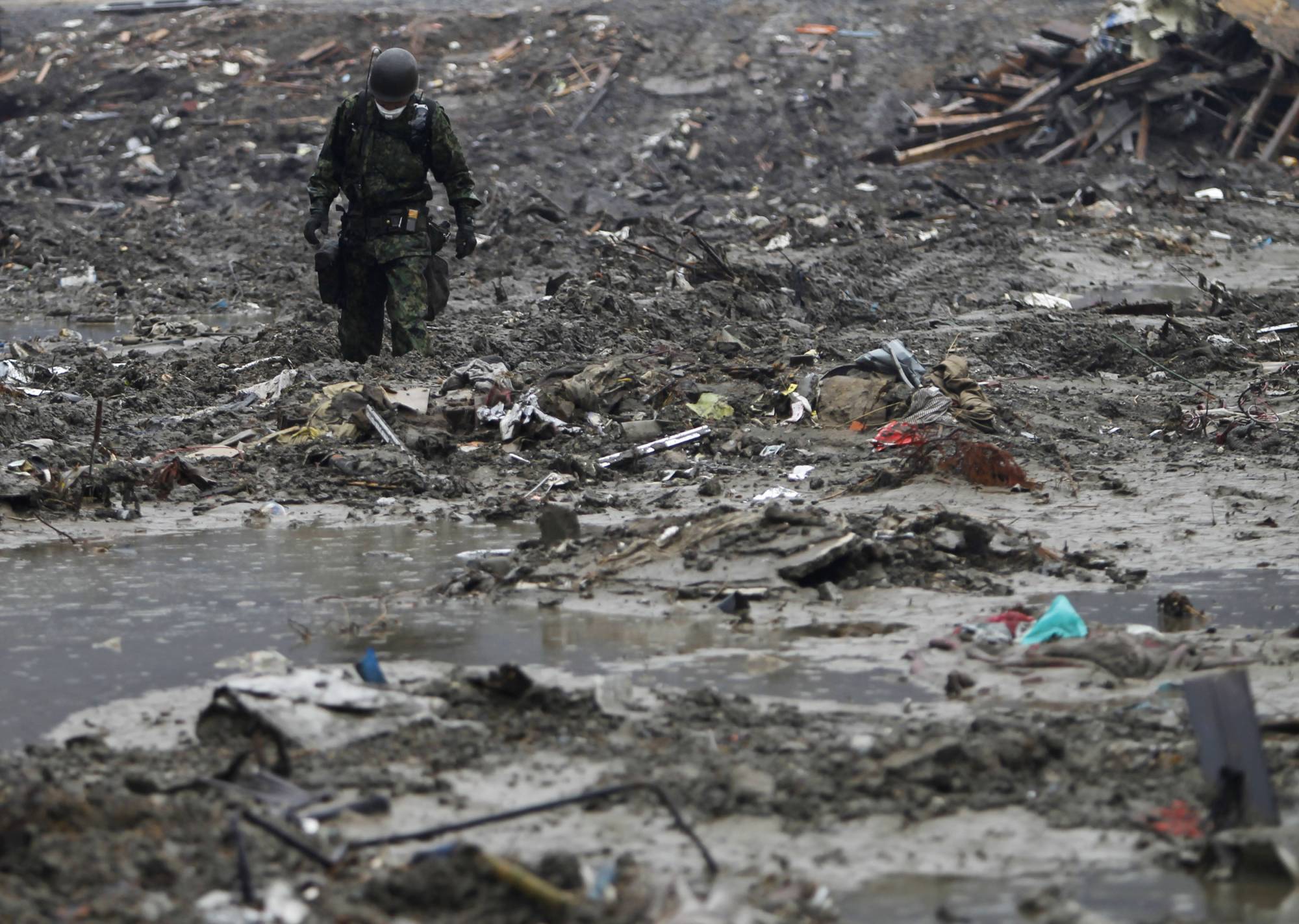 A Self-Defense Force member searches for victims in an area devastated in the March 11, 2011, earthquake and tsunami, in Minamisanriku, Miyagi Prefecture, in April 2011. | REUTERS