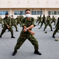 Ground Self-Defense Force members hold morning preparatory exercises at their camp on Miyako Island in Okinawa Prefecture in April. | REUTERS
