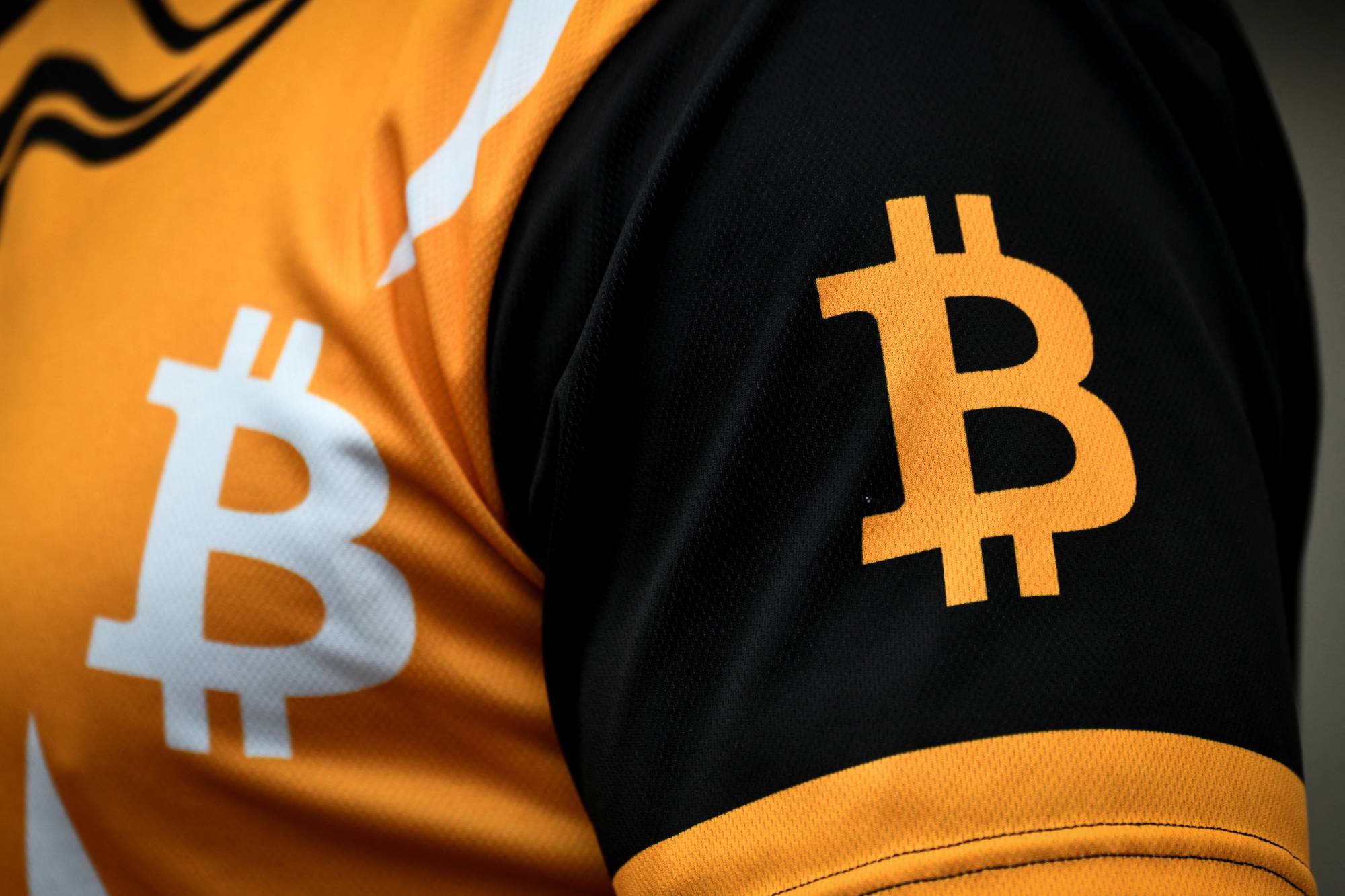 A man wears a t-shirt with the logo of bitcoin as he waits for Sam Bankman-Fried, the founder and former CEO of cryptocurrency exchange FTX, to attend a hearing at the Magistrate Court building in Nassau, Bahamas, on Dec. 19. | REUTERS