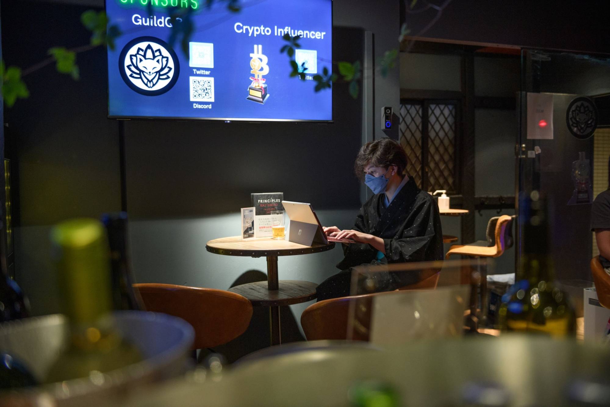 A barkeeper uses a laptop computer inside CryptoBar P2P in the Ginza district of Tokyo in June. | BLOOMBERG