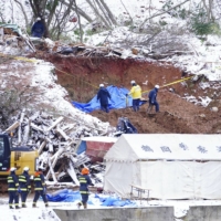 Police officers search for missing people in Tsuruoka, Yamagata Prefecture, on Monday following a landslide. | KYODO