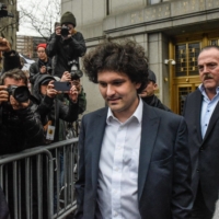 Sam Bankman-Fried, co-founder of FTX Cryptocurrency Derivatives Exchange (center), departs from court in New York on Tuesday. | BLOOMBERG