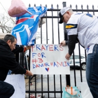 Football fans tape a sign to a fence during a vigil outside the University of Cincinnati Medical Center where Bills safety Damar Hamlin lies in critical condition in Cincinnati on Tuesday. | REUTERS