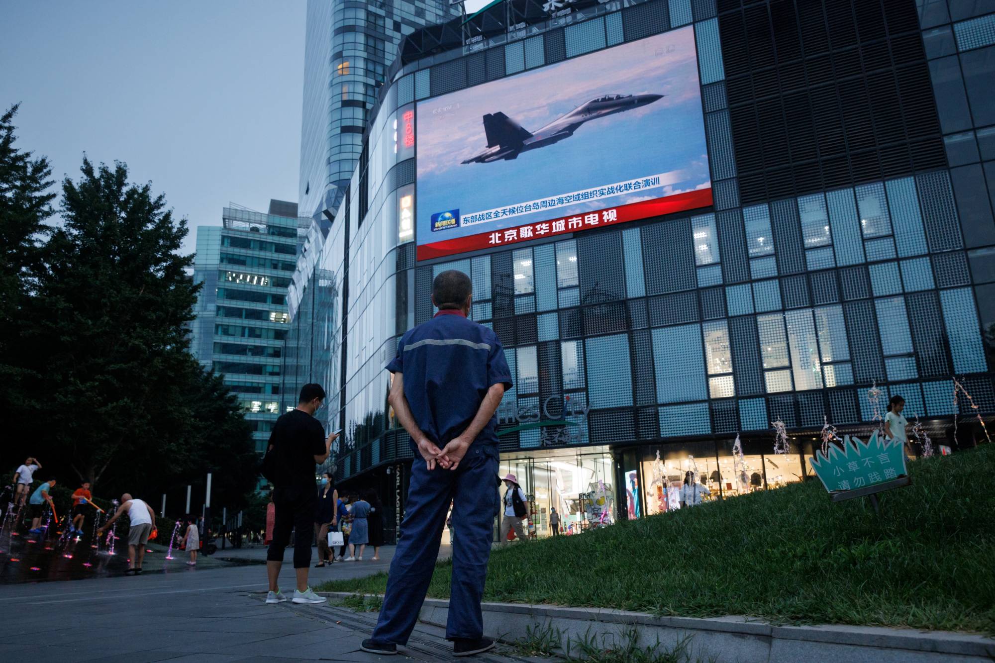 A man watches a news broadcast showing a Chinese fighter jet during joint military operations near Taiwan, at a shopping center in Beijing last August. China sent a contingent of 57 warplanes around Taiwan in the 24 hours through Monday morning, Taipei said. | REUTERS