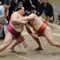 Mitakekai grapples with  Hoshoryu (right) during Day 3 of the New Year Grand Sumo Tournament at the Ryogoku Kokugikan in Tokyo on Tuesday. | KYODO