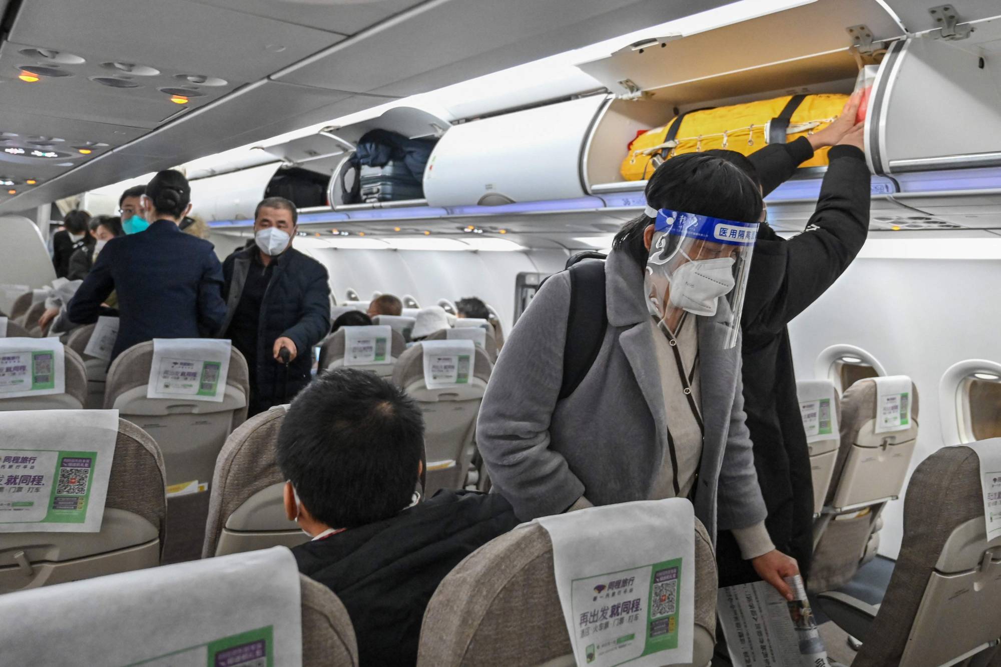 A passenger wearing a face shield and mask boards a domestic flight at Shanghai Pudong International Airport in Shanghai on Jan. 3. | AFP-JIJI