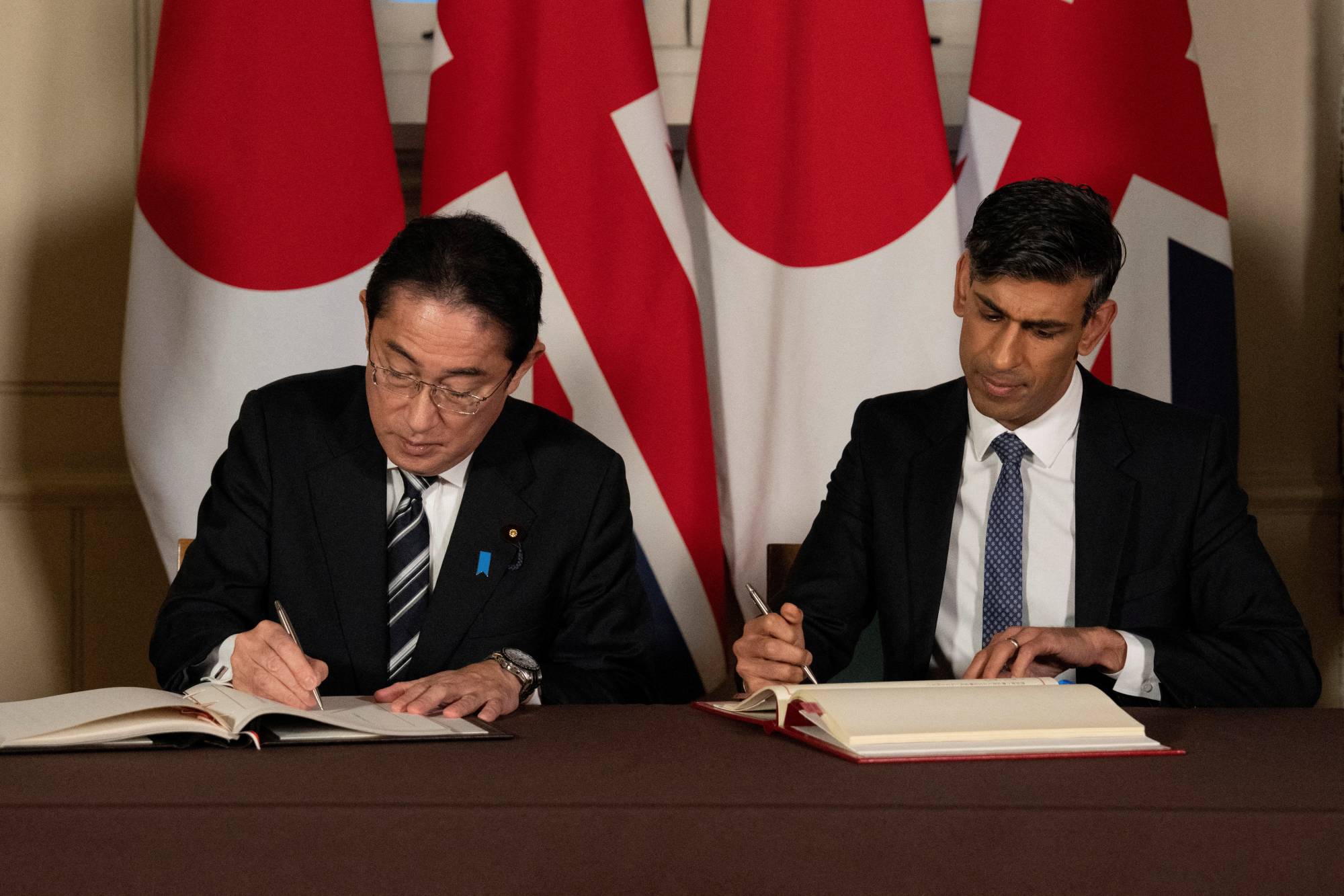 Prime Minister Fumio Kishida and British leader Rishi Sunak sign a Reciprocal Access Agreement at the Tower of London in the British capital on Wednesday.  | POOL / VIA REUTERS