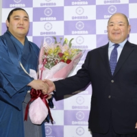 Okinoumi (left) poses with stablemaster Hakkaku after announcing his retirement from professional sumo at Ryogoku Kokugikan on Saturday. | KYODO
