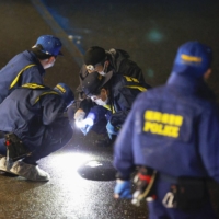 Police officers examine the site where a woman was fatally stabbed near JR Hakata Station on Monday. | KYODO