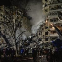 Civilians and emergency responders at an apartment complex in Dnipro, Ukraine, on Jan. 14 after a deadly Russian missile strike. | NICOLE TUNG / THE NEW YORK TIMES