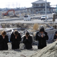 A family prays for relatives who were killed in the March 11, 2011, earthquake and tsunami, in Ishinomaki, Miyagi Prefecture, on March 11, 2012. | REUTERS