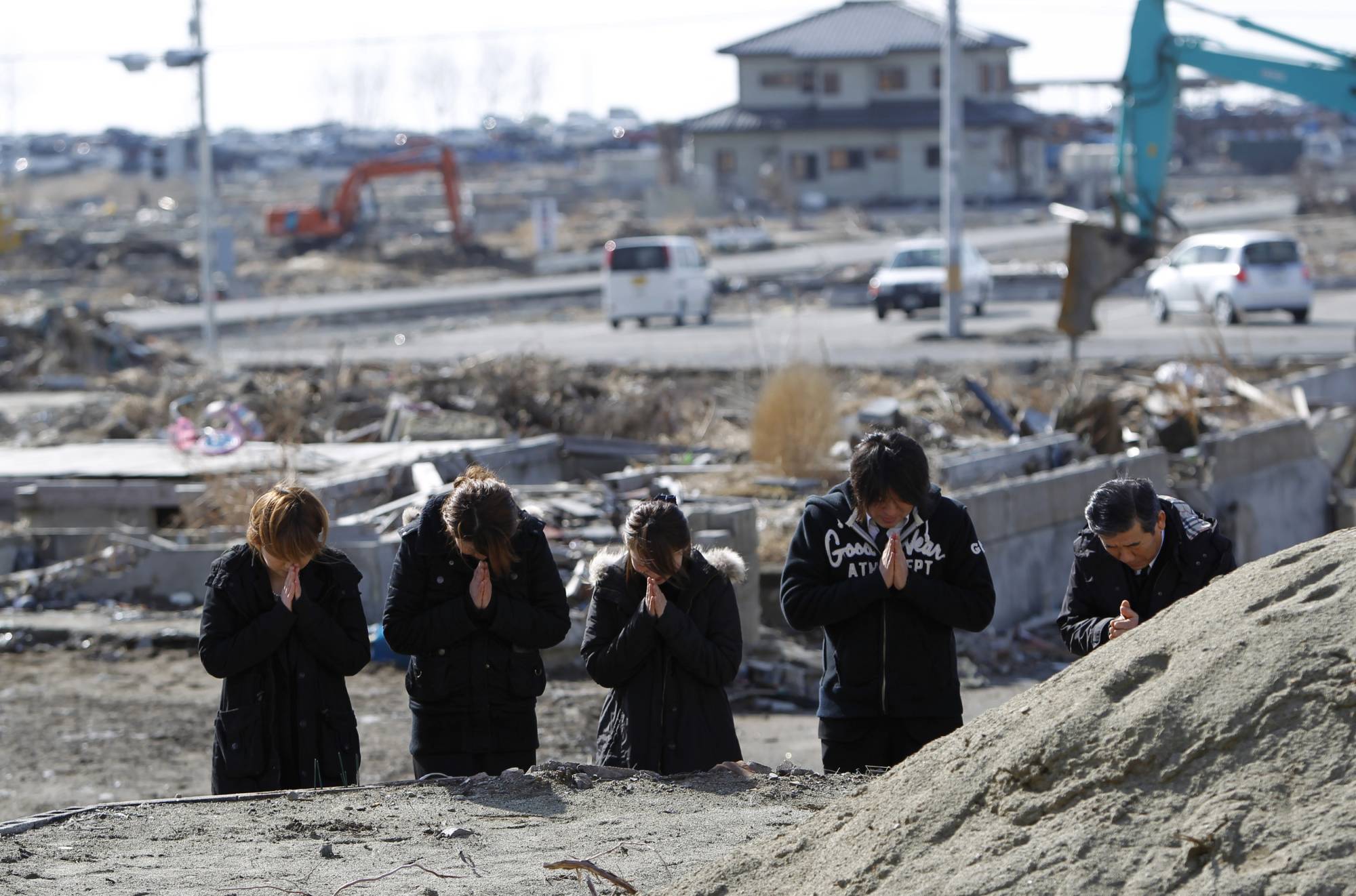 A family prays for relatives who were killed in the March 11, 2011, earthquake and tsunami, in Ishinomaki, Miyagi Prefecture, on March 11, 2012. | Reuters