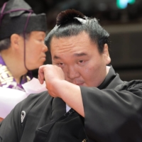Former yokozuna Hakuho, now known as Miyagino stablemaster, wipes away tears during his topknot-cutting ceremony at Ryogoku Kokugikan on Saturday. | POOL / VIA KYODO