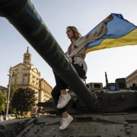 A Ukrainian wrapped in the country\'s flag at Maidan Square in Kyiv during a parade of captured Russian tanks in August last year.  | LYNSEY ADDARIO / THE NEW YORK TIMES