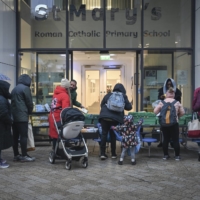 Staff members give out food and household items at a temporary food bank at St. Mary\'s Roman Catholic Primary School in the Battersea neighborhood of London on Jan. 11. | MARY TURNER / THE NEW YORK TIMES