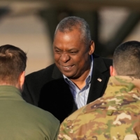 U.S. Secretary of Defense Lloyd Austin is greeted by military officials upon his arrival at the Osan Air Base in Pyeongtaek, South Korea, on Monday.  | POOL / VIA REUTERS