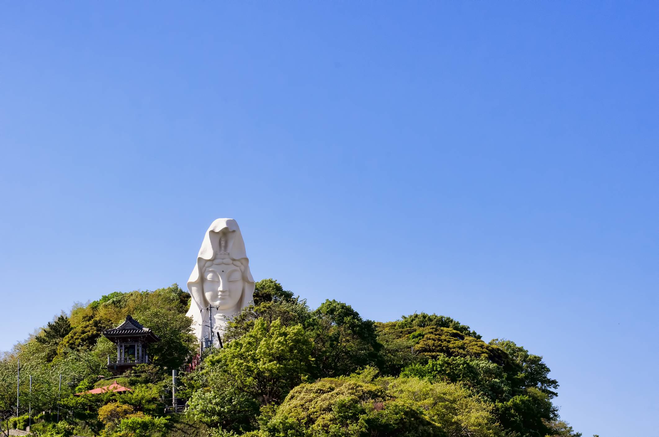 The statue at Ofuna Kannon Temple in Kanagawa Prefecture peeks out from the trees surrounding the area. | GETTY IMAGES