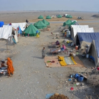 Internally displaced flood-affected people sit around a makeshift camp in the area of Dera Allah Yar on Jan. 9. | AFP-JIJI