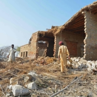 Flood-affected residents collect bricks from the debris of their damaged house in Dera Allah Yar on Jan. 9. | AFP-JIJI
