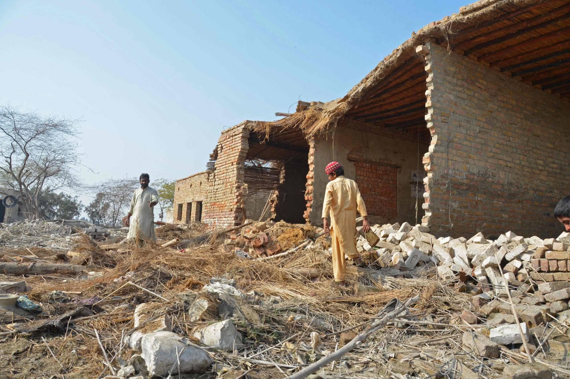 Flood-affected residents collect bricks from the debris of their damaged house in Dera Allah Yar on Jan. 9. | AFP-Jiji