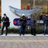 People use their smartphones on a street in Tokyo in 2019. | REUTERS