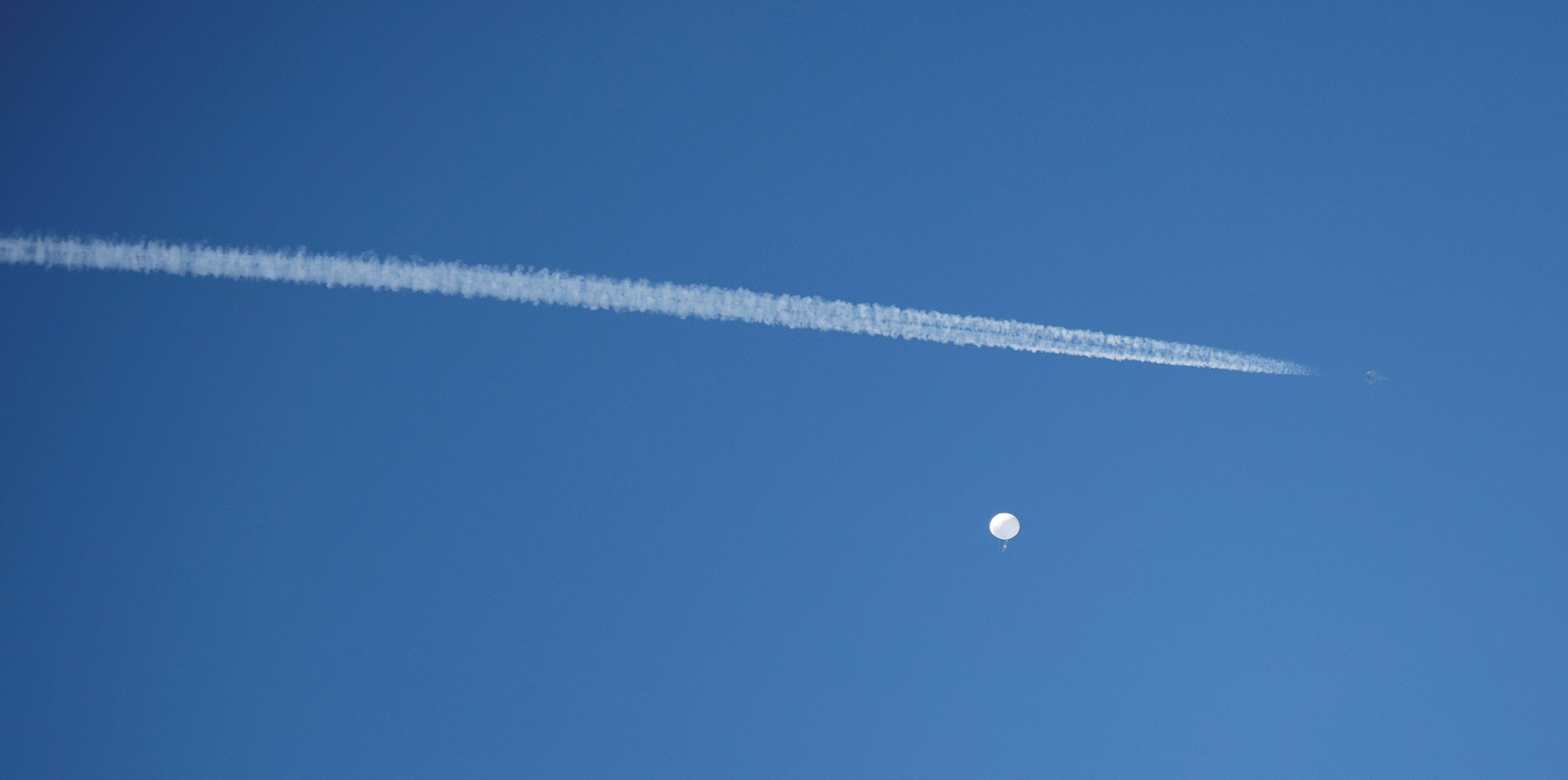 A U.S. fighter jet flies by a suspected Chinese spy balloon before the balloon was shot down off the coast of Surfside Beach, South Carolina, on Saturday. | REUTERS