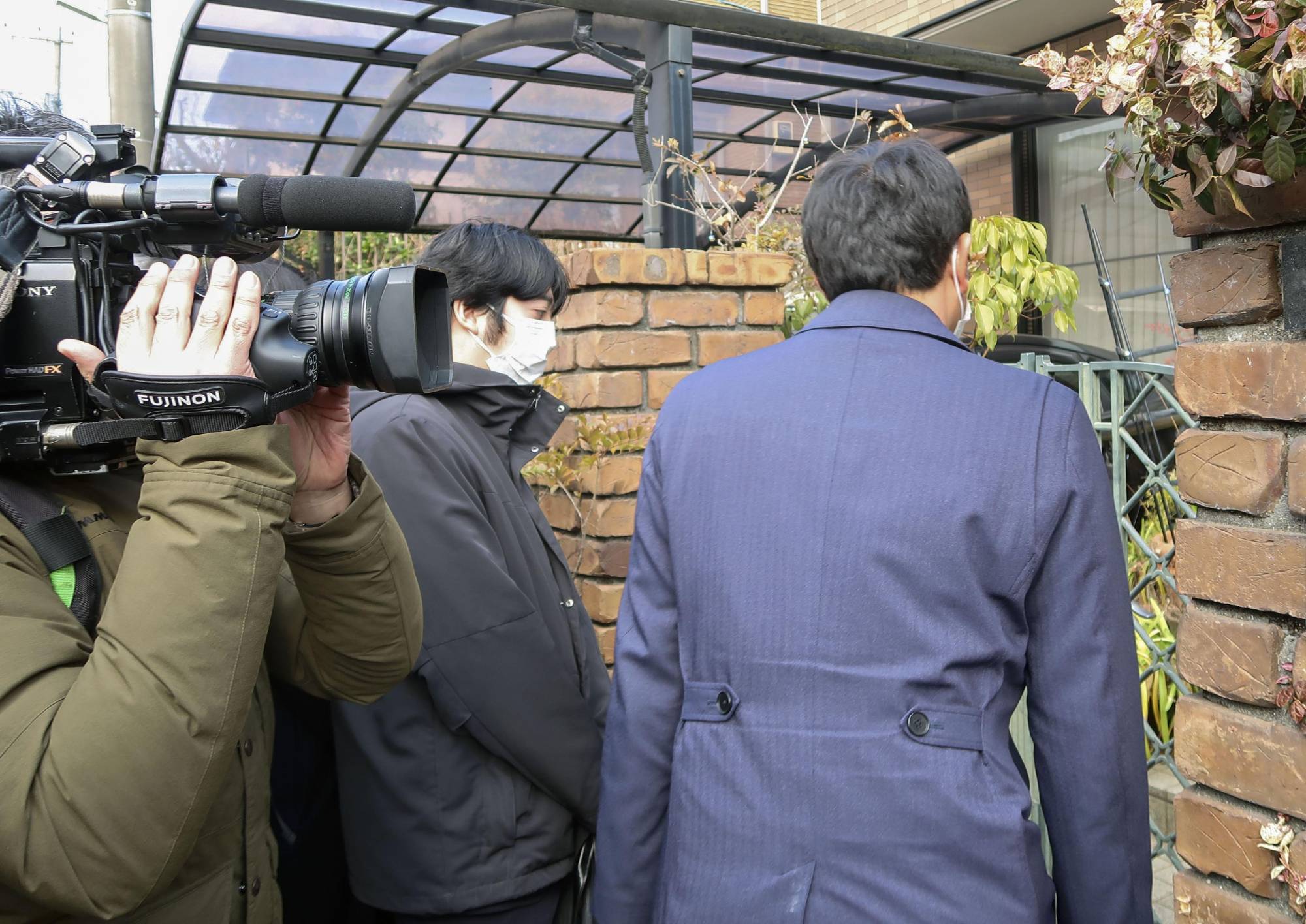 Officers of the Tokyo Prosecutor's Office raid the house of a former operations executive at the Tokyo Olympics organizing committee in Kawasaki Wednesday. | KYODO