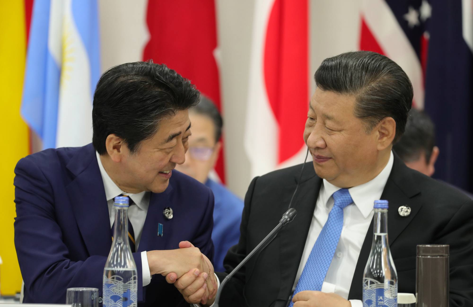 Prime Minister Shinzo Abe shakes hands with Chinese leader Xi Jinping during a G20 summit in Osaka in June 2019. | SPUTNIK / KREMLIN / VIA REUTERS
