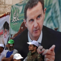Syrians and Palestinians living in Syria stand next to a poster depicting Syria\'s President Bashar al-Assad as they mark the annual al-Quds Day (Jerusalem Day), in Damascus, Syria, in April last year. | REUTERS