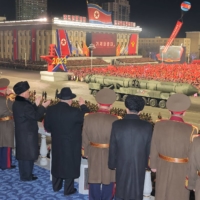 North Korean leader Kim Jong Un and military officials watch as what analysts say could be a mock-up of a new solid-fueled intercontinental ballistic missile is displayed during a military parade to mark the 75th founding anniversary of North Korea\'s army, in Pyongyang\'s Kim Il Sung Square on Wednesday.    | KCNA / VIA REUTERS