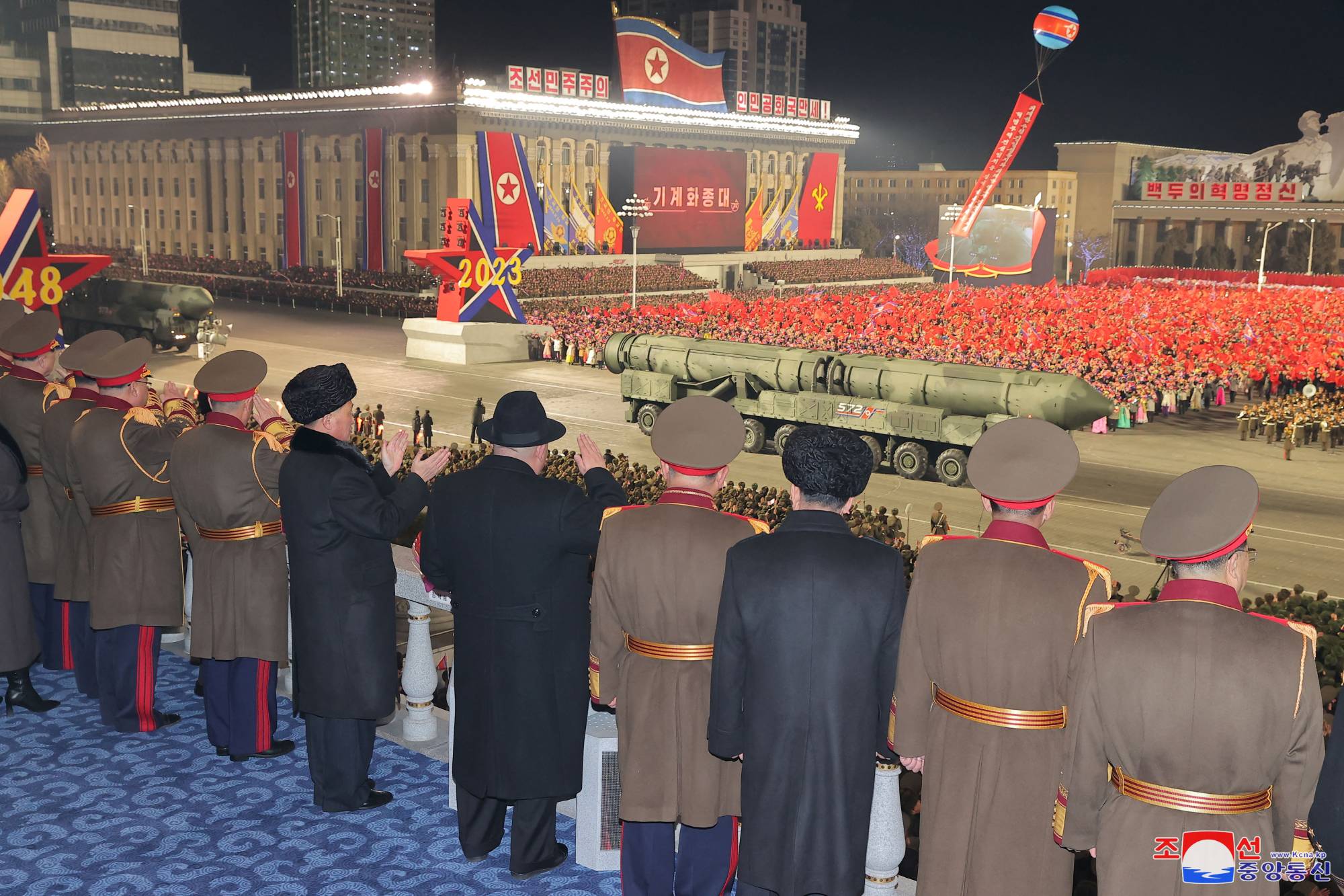 North Korean leader Kim Jong Un and military officials watch as what analysts say could be a mock-up of a new solid-fueled intercontinental ballistic missile is displayed during a military parade to mark the 75th founding anniversary of North Korea's army, in Pyongyang's Kim Il Sung Square on Wednesday. | KCNA / via REUTERS
