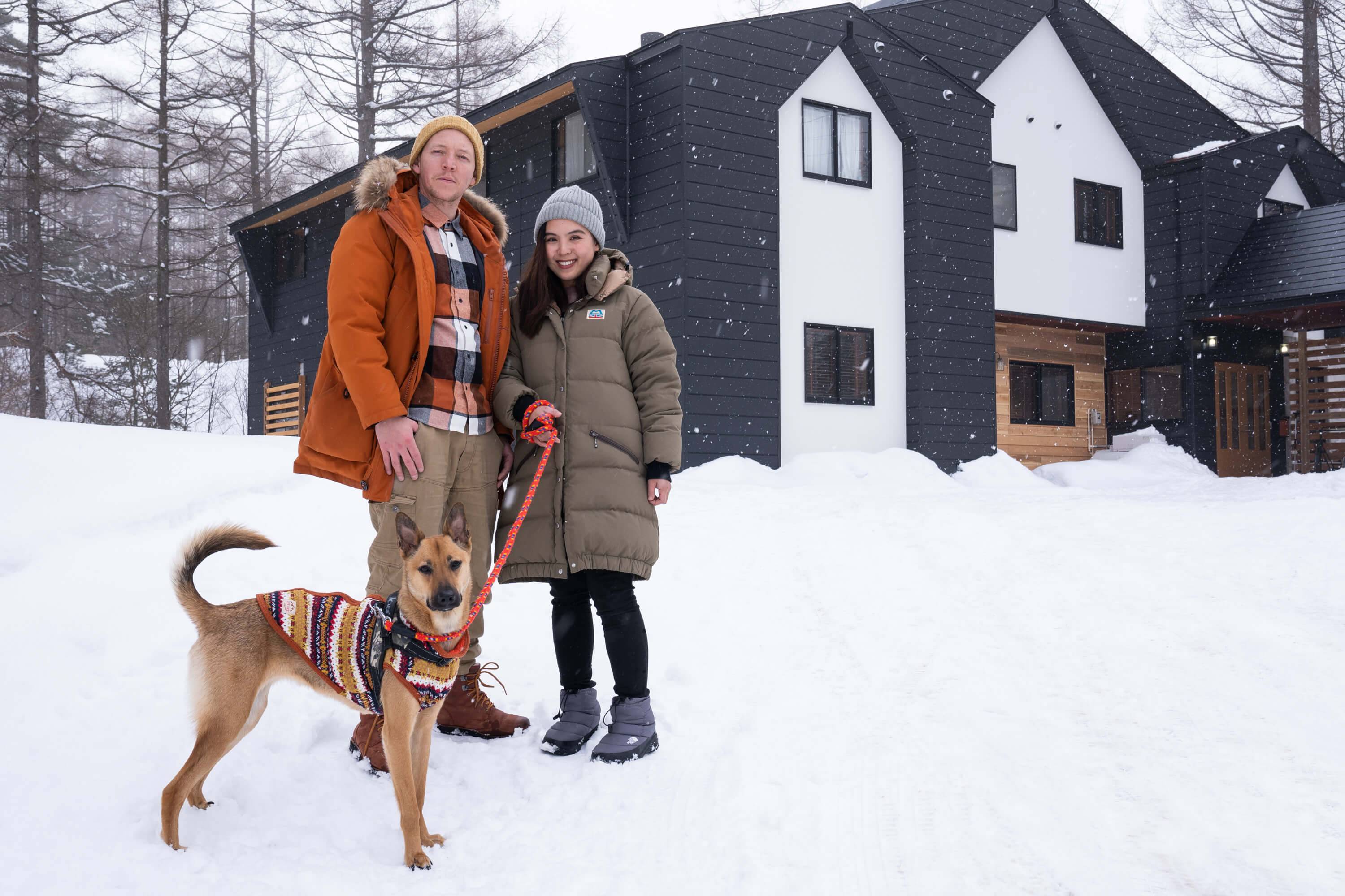 Justin and Kaori Sereni pose with their dog Tito in front of Onpoint Madarao, the boutique ski lodge they opened in 2020. | BEN BEECH