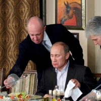 Yevgeny Prigozhin (left) assists Vladimir Putin during a dinner with foreign scholars and journalists outside Moscow in November 2011. | REUTERS