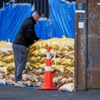 A man stacks sandbags to protect a warehouse before the arrival of Cyclone Gabriele in Auckland, New Zealand, on Sunday. 

  | REUTERS