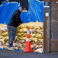 A man stacks sandbags to protect a warehouse before the arrival of Cyclone Gabriele in Auckland, New Zealand, on Sunday. 

  | REUTERS