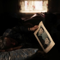 Volodymyr Kovalyov, 77, looks at a photo of himself and his brother, Stepan Kovalyov, as he lays in bed  | REUTERS