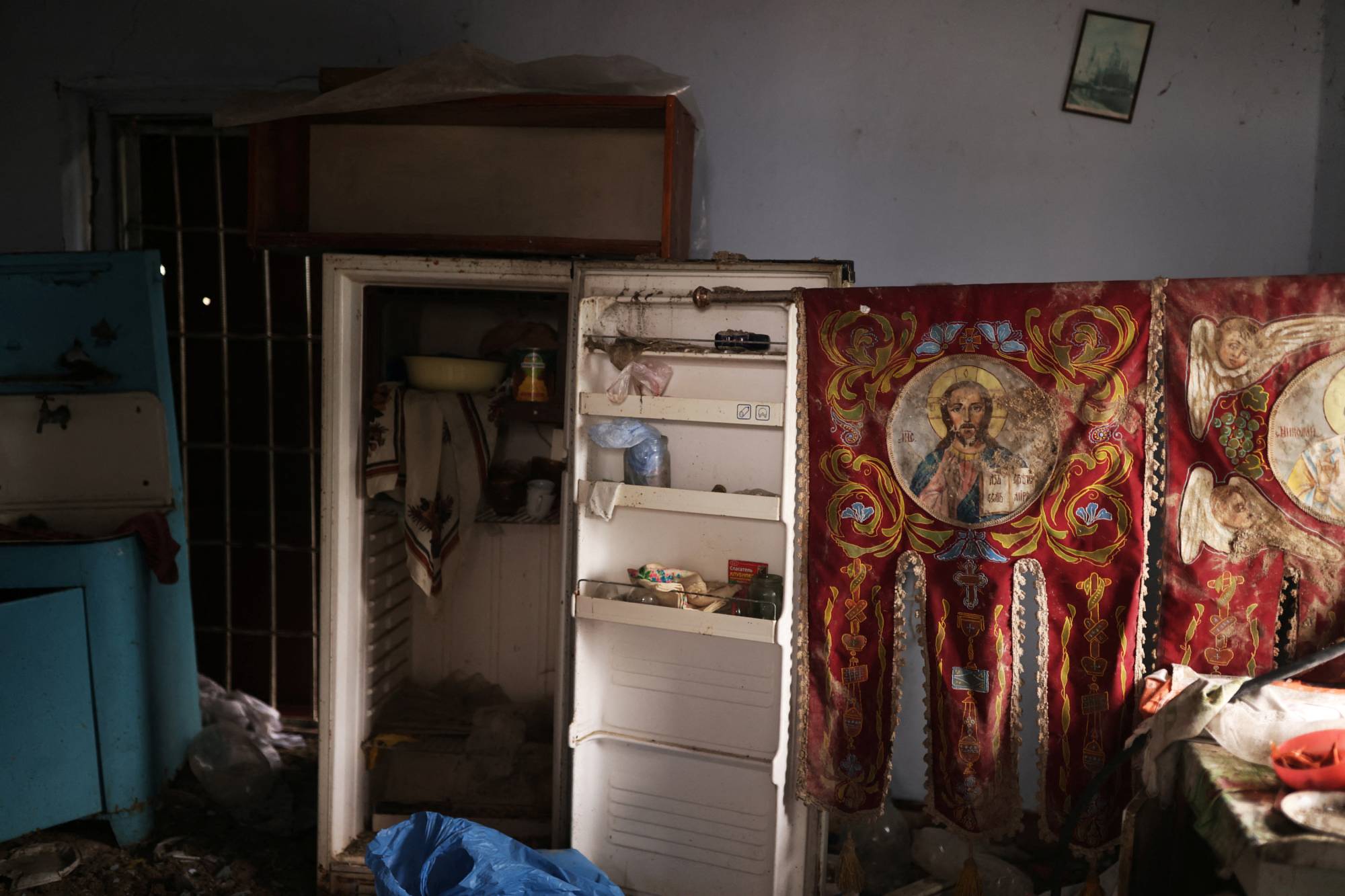 Religious iconography is displayed in a destroyed house, once lived in by an Orthodox priest but abandoned during the months of Russian occupation, nearby the cemetery in the village of Posad-Pokrovske | REUTERS