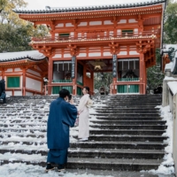 A woman poses for a photo on the snow-covered steps of the Yasaka Shrine in Kyoto on Jan. 25.  | AFP-JIJI