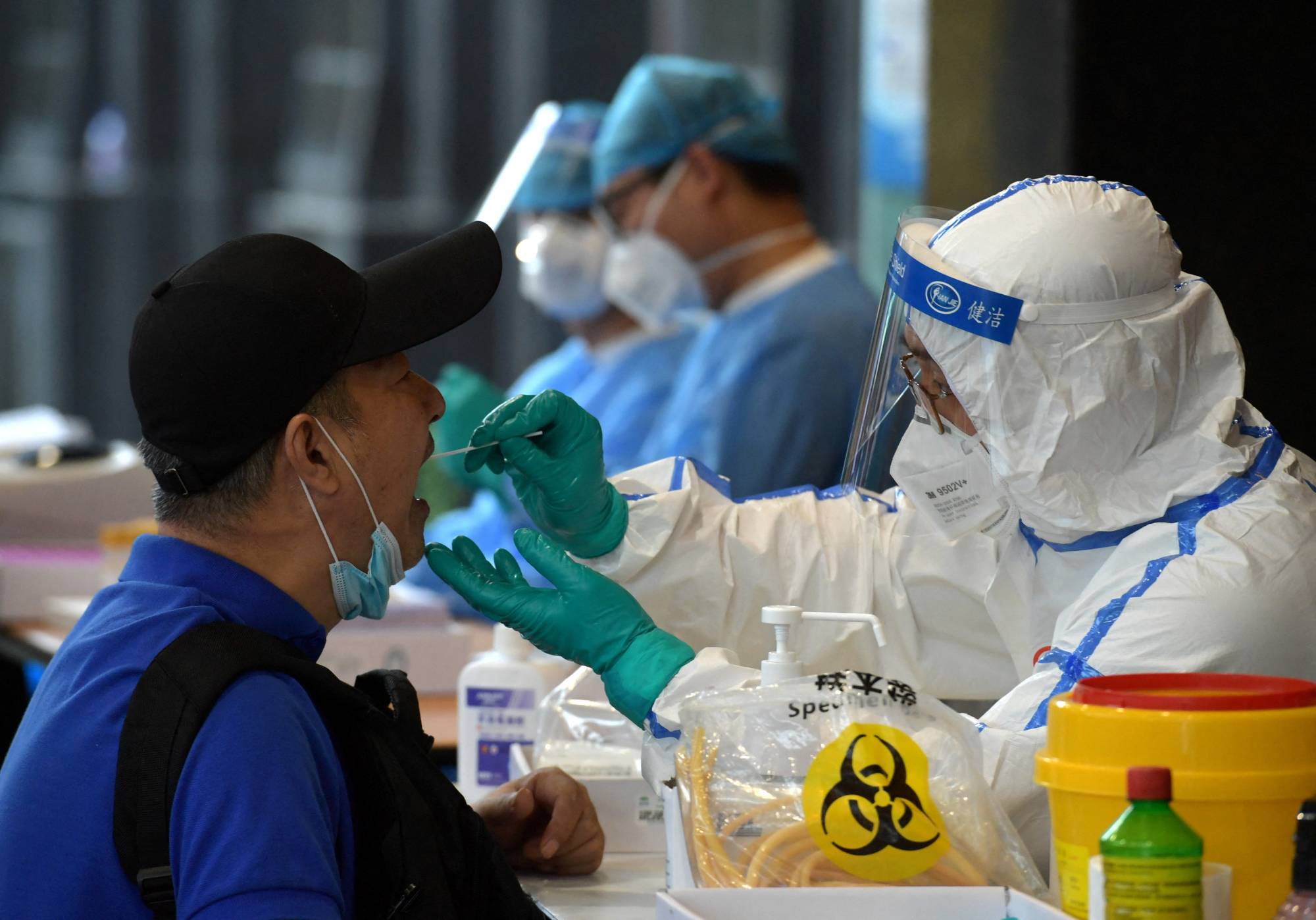 A medical staff in protective suit collects swabs from people who have recently traveled to Beijing for nucleic acid tests, in Nanjing, China, in 2020. | CHINA DAILY / VIA REUTERS 
