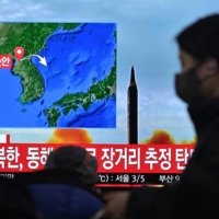 A woman in Seoul walks past a television showing a news broadcast of a North Korean missile test on Saturday. | AFP-JIJI