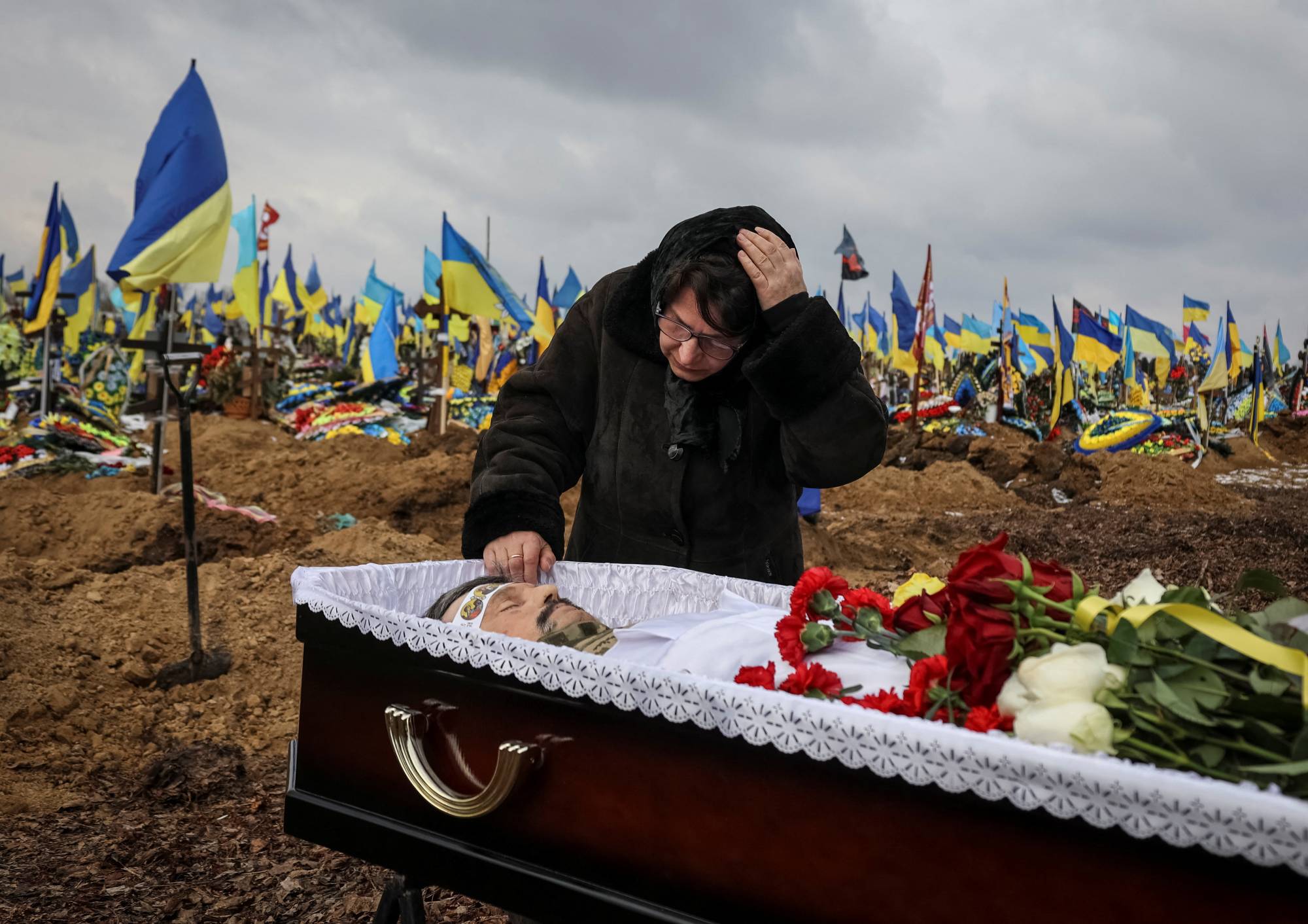 A Ukrainian woman buries her husband at a cemetery in Kharkiv, Ukraine, on Feb. 16. The soldier died while fighting Russian troops. REUTERS  | REUTERS
