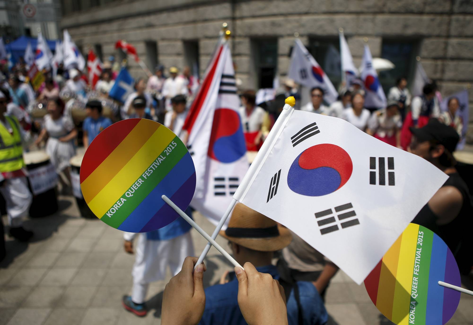 A participant holds up a rainbow and a South Korean national flag as they face Christian groups against homosexuality, during the Korea Queer Festival in Seoul on June 28, 2015.  | REUTERS