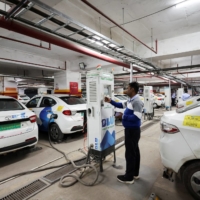 A man charges an electric vehicle (EV) at the charging hub of Indian ride-hailing BluSmart Electric Mobility in Gurugram, India, on Dec. 9. | REUTERS