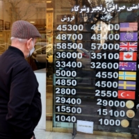 A man looks at currency exchange rates at a shop in Tehran on Tuesday. | AFP-JIJI