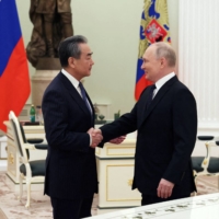 Russian President Vladimir Putin shakes hands with Wang Yi, China\'s top diplomat, during a meeting in Moscow on Wednesday. | POOL / SPUTNIK / VIA REUTERS