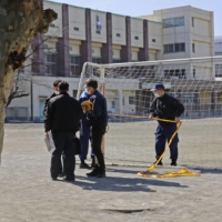 Saitama Prefectural Police investigate an elementary school yard in the city of Saitama where the body of a cat was found on Feb. 17. | KYODO