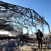 Grain farmer Andrii Povod inspects a destroyed barn at his farm in Bilozerka, in Ukraine\'s Kherson region, on Feb. 20. | REUTERS 