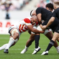 Japan\'s Michael Leitch (left) attempts to stop New Zealand from advancing the ball during their match in Oct. 2022 in Tokyo. | KYODO